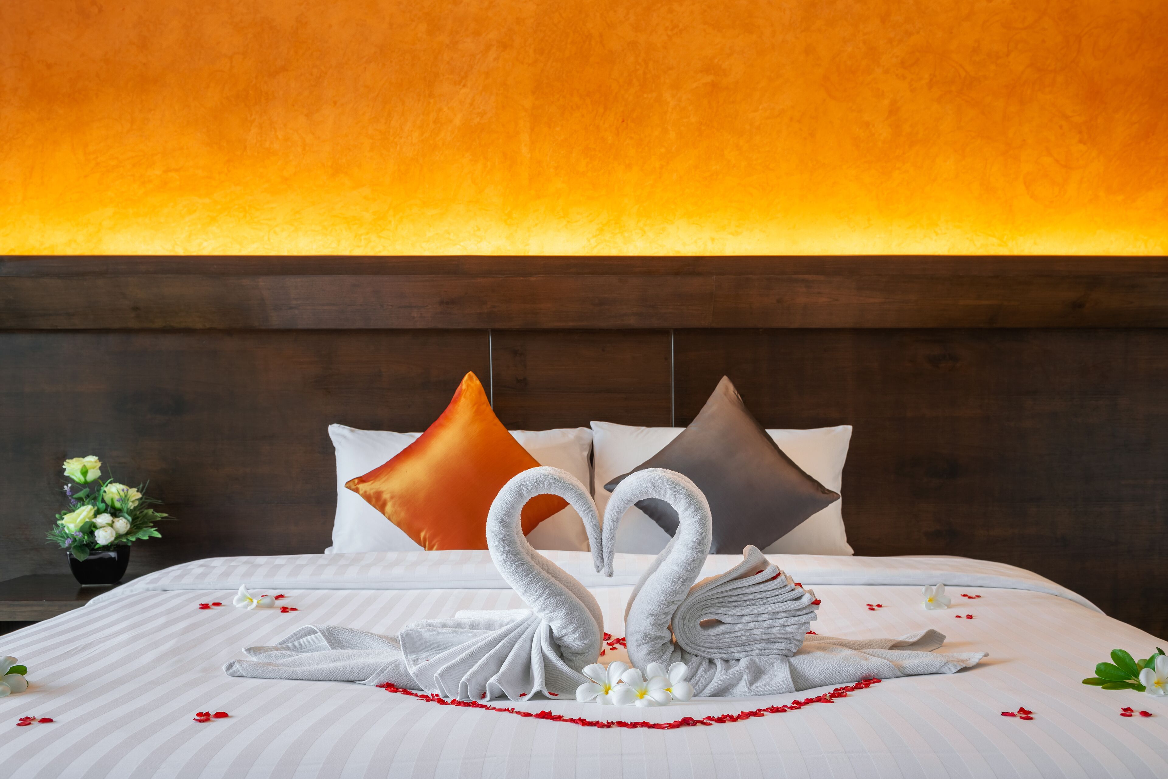 A hotel room with a bed, pillows, and a decorative swan arrangement.