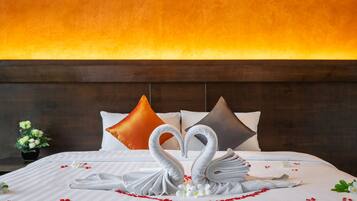A hotel room with a bed, pillows, and a decorative swan arrangement.