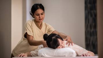 A massage therapy session in a room with a plain wall and a curtain.