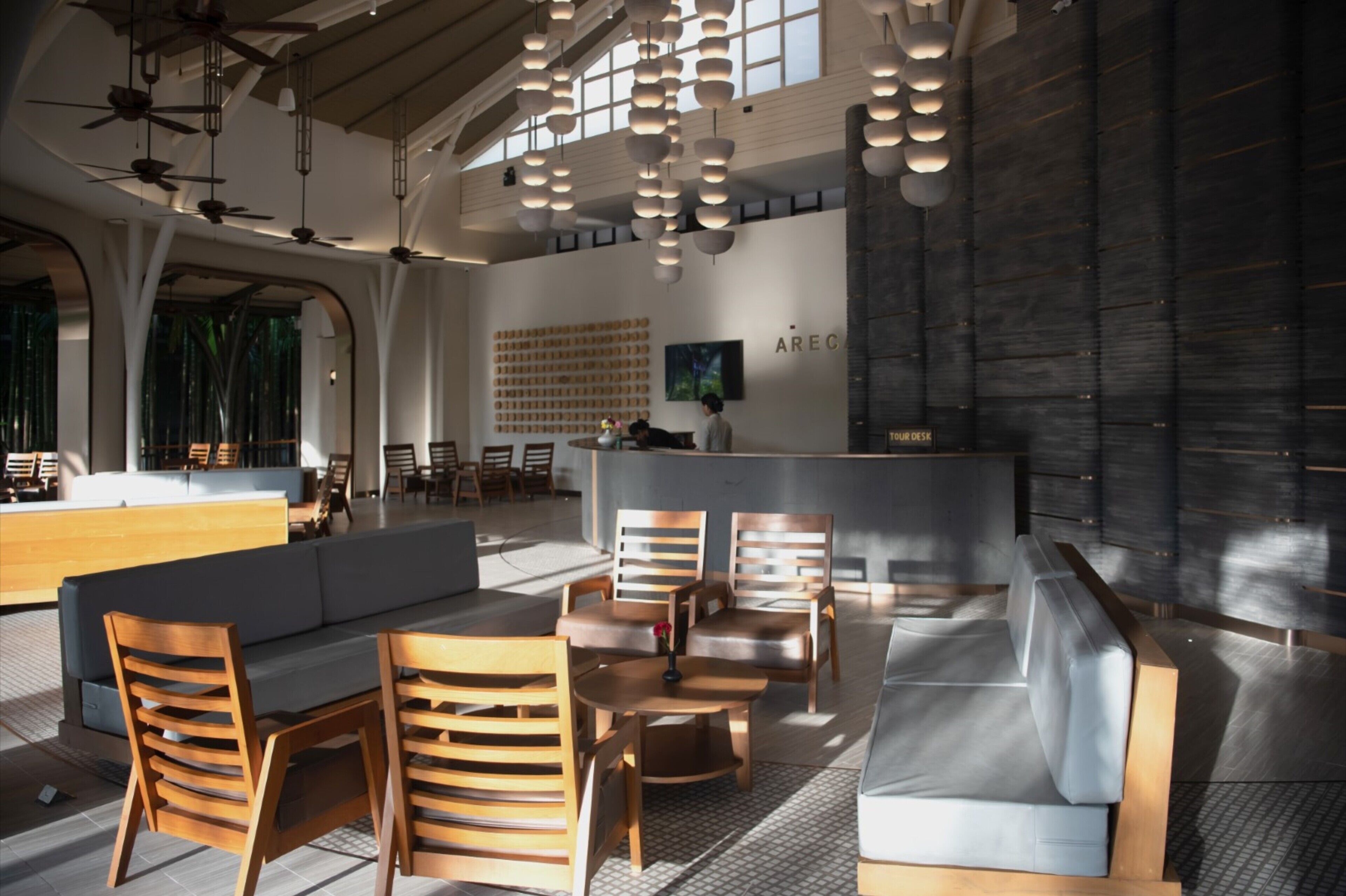 A modern hotel lobby with a reception desk, seating area, and a large wall with a grid of framed pictures.