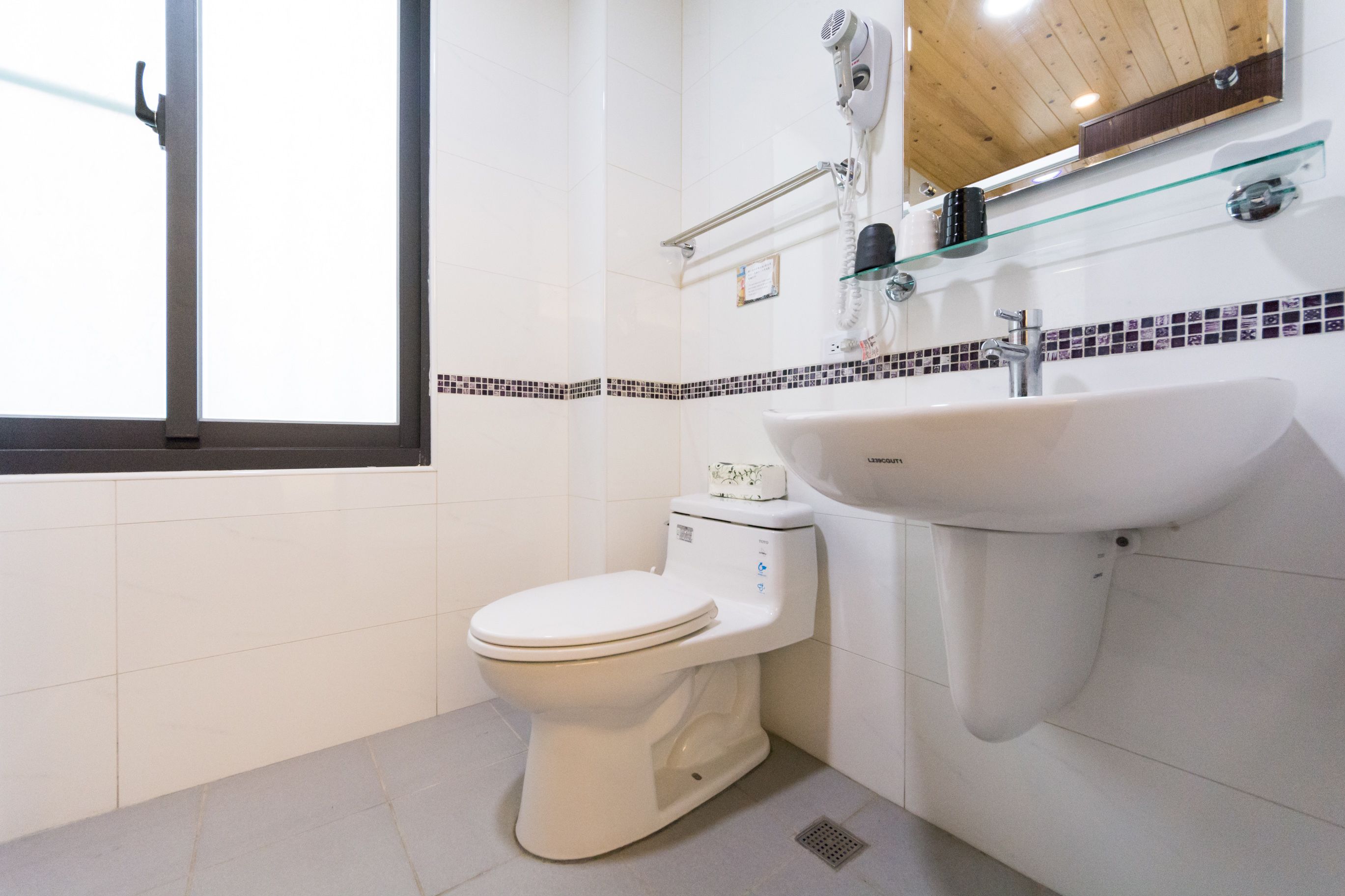 Ein Badezimmer mit Toilette, Waschbecken und einem Fenster.