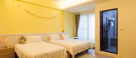 A hotel room with two beds, a small bedside table with a lamp, a teddy bear, and a curtain.