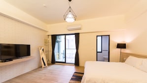 Habitación de hotel moderna con una cama grande, televisión de pantalla plana, suelo de madera y un balcón con vistas.