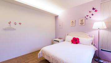 A bedroom with a bed, bedside table, lamp, and wall decorations.