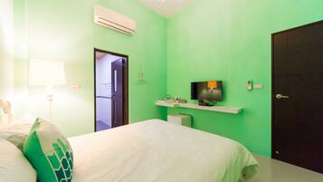 A room with a bed, a TV mounted on the wall, a door, and a wall-mounted air conditioner.