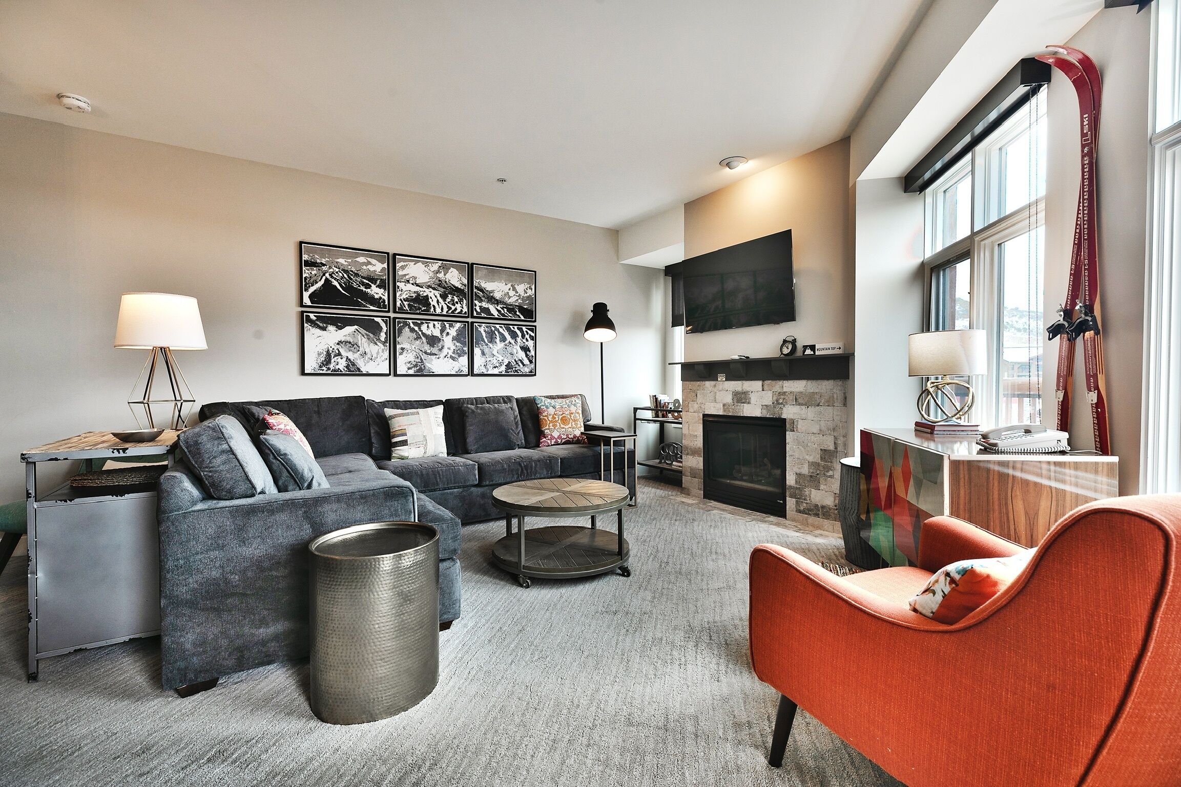 Una sala de estar moderna con un sofá gris, un sillón rojo, una mesa de centro y una chimenea.