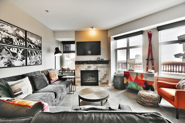 A modern living room with a fireplace, a sofa, a coffee table, and a TV mounted on the wall.