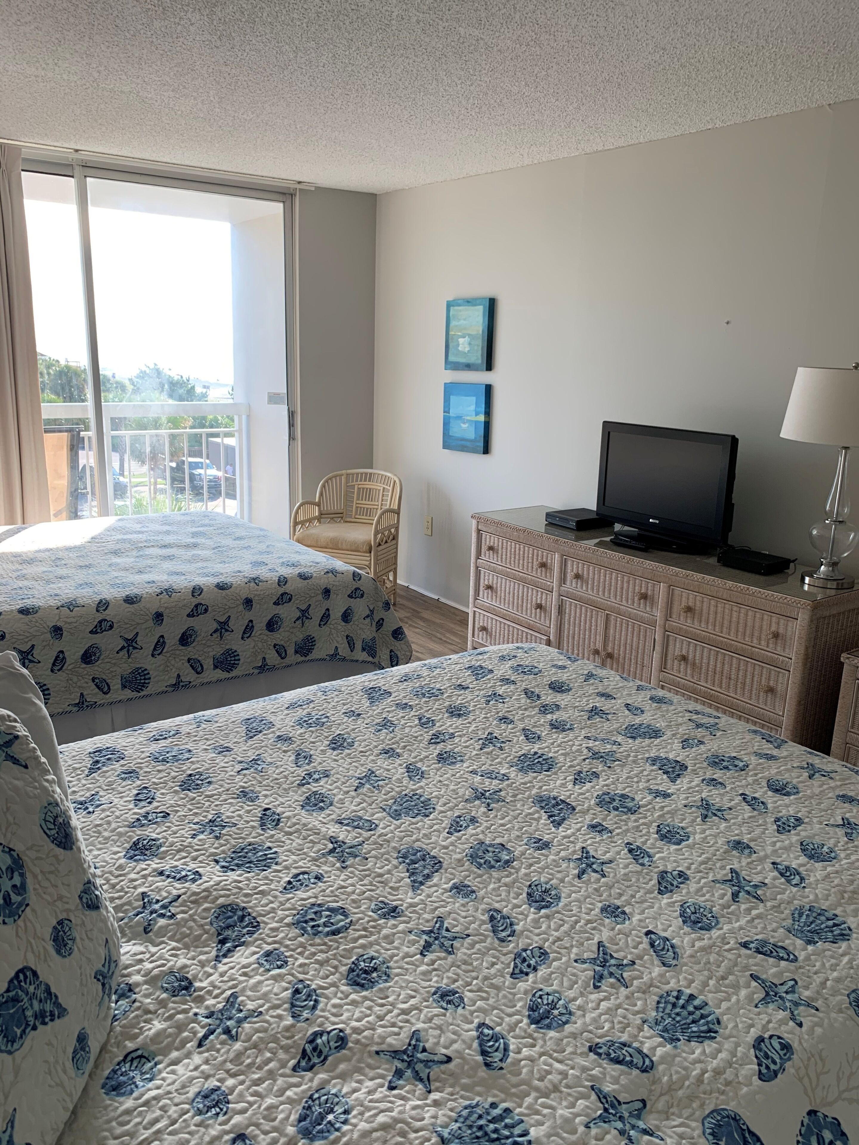 A hotel room with two beds, a television, a dresser, and a chair.