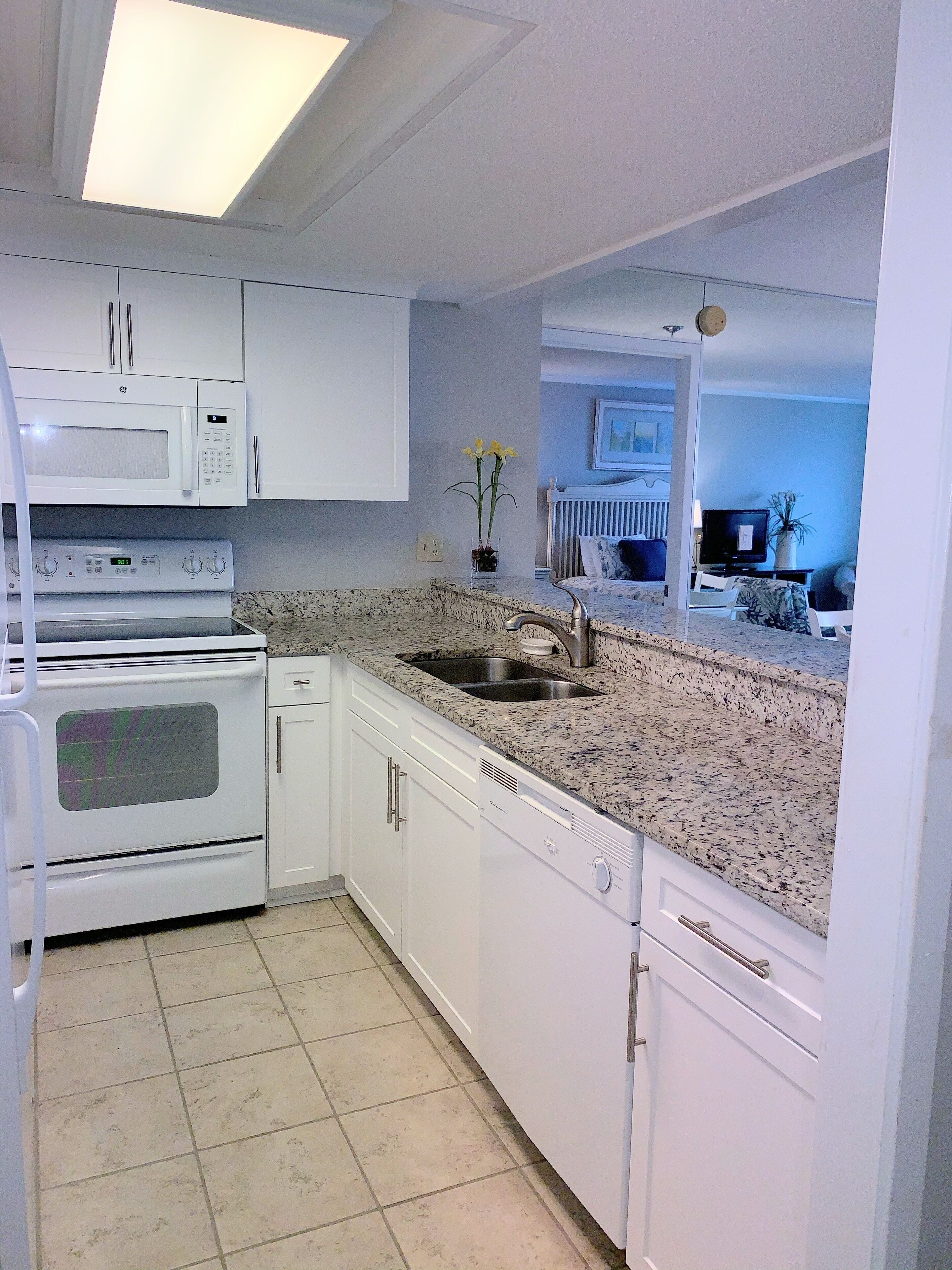 A kitchen with white cabinets, a microwave, an oven, a dishwasher, and a granite countertop.