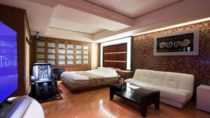 A modern hotel room with a massage chair, a sofa, a flat-screen TV, and a large window. - HOTEL PERRIER - Adults Only (Tokyo)
