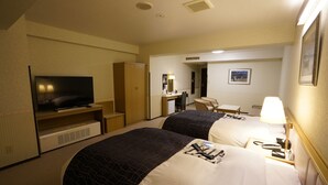 Een hotelkamer met twee bedden, een televisie, een bureau, een stoel en een lamp.