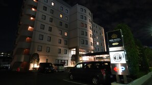 Een meerlaags hotel met verlichte ramen en een bord waarop APA Hotel staat.