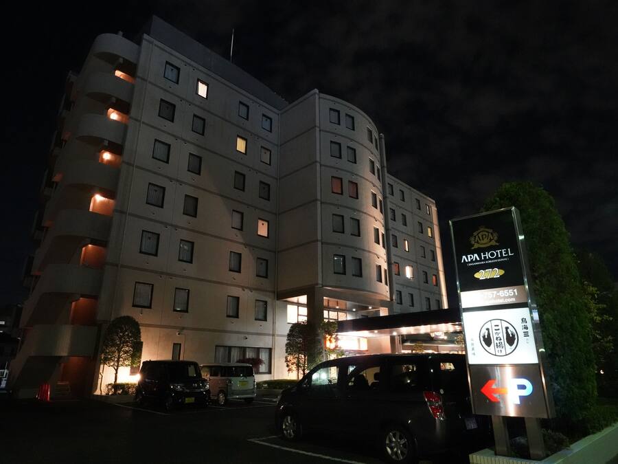 A multi-story hotel with illuminated windows and a sign indicating it is APA Hotel.
