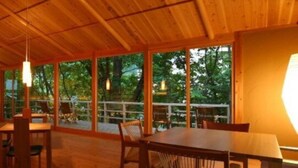 Un intérieur en bois, avec de grandes fenêtres, une table et des chaises.