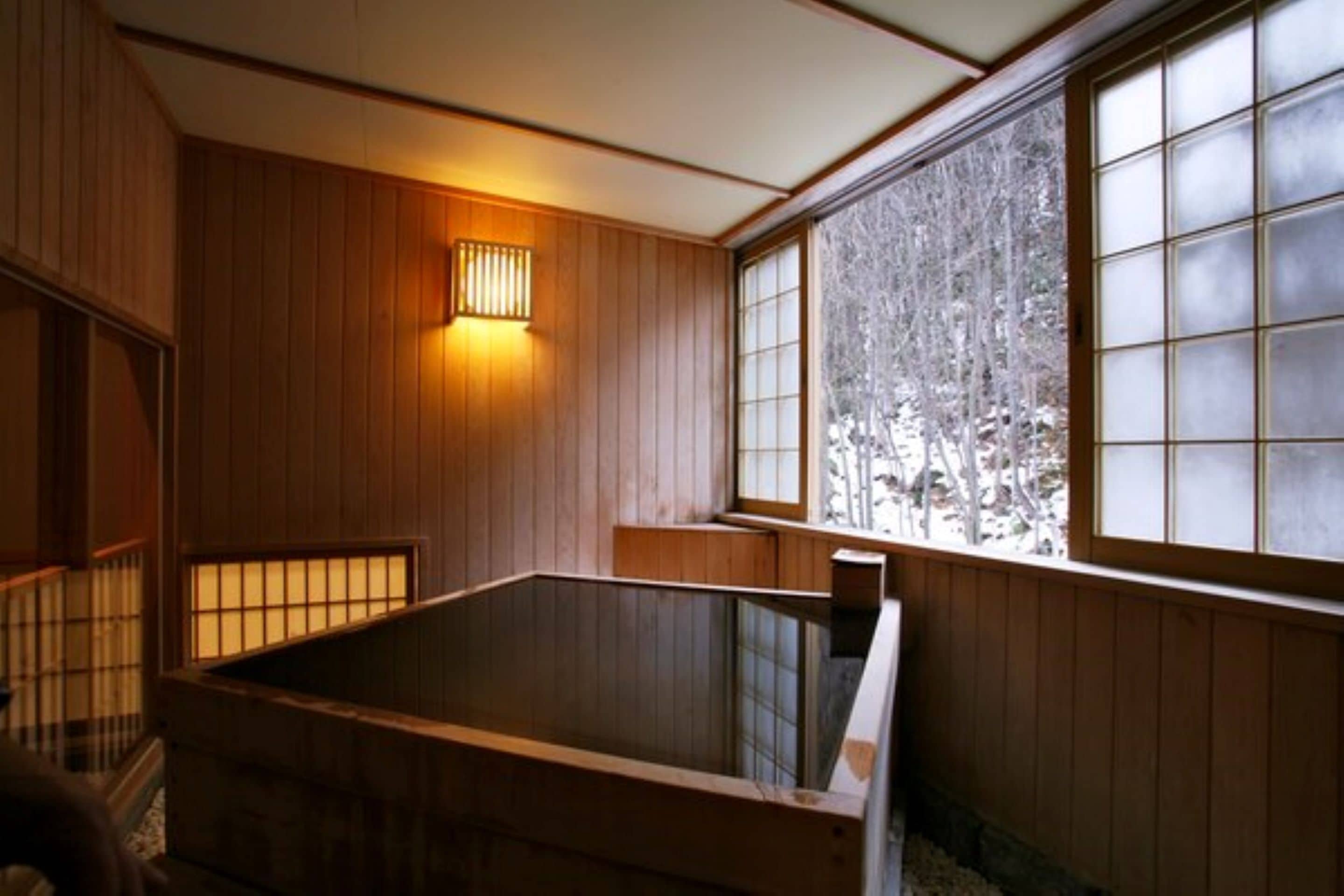 Un onsen japonés tradicional con paredes de madera y un ventanal grande.