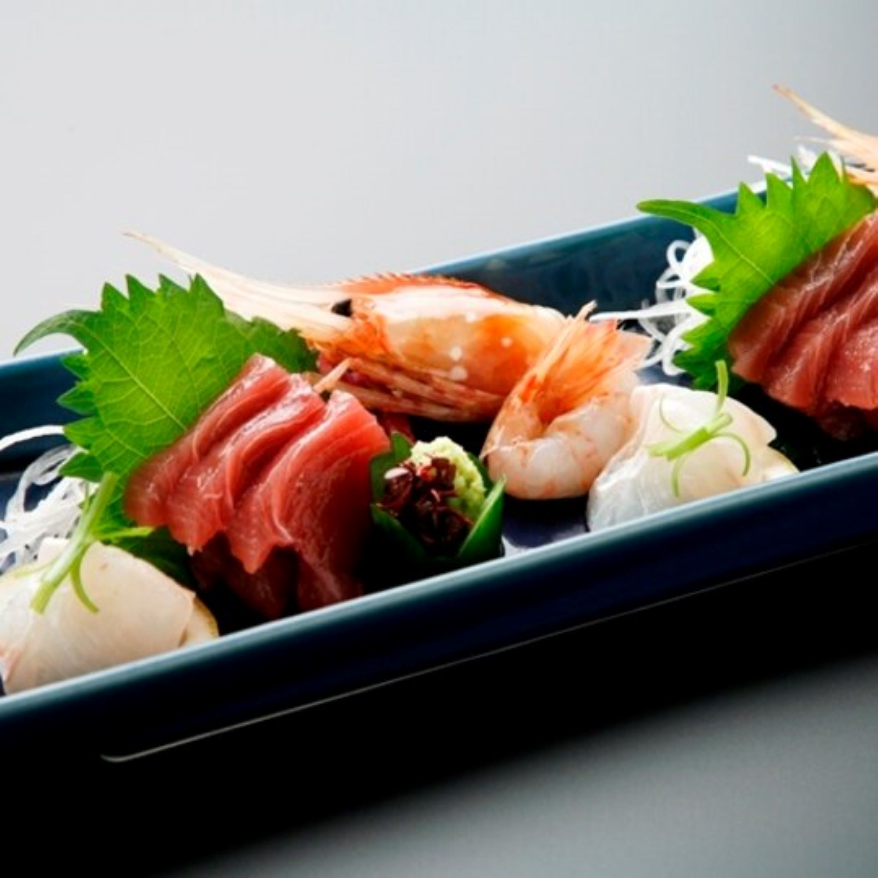 Ett urval av sushi på en mörk tallrik.