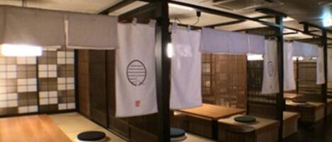 A row of wooden tables with stools, each separated by a curtain with a logo.