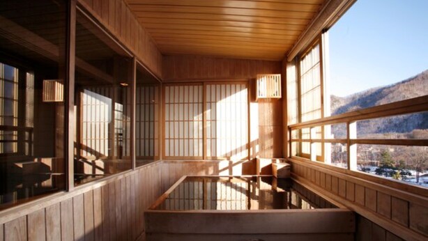 Un onsen japonais traditionnel, avec un décor intérieur en bois et une vue sur les montagnes.