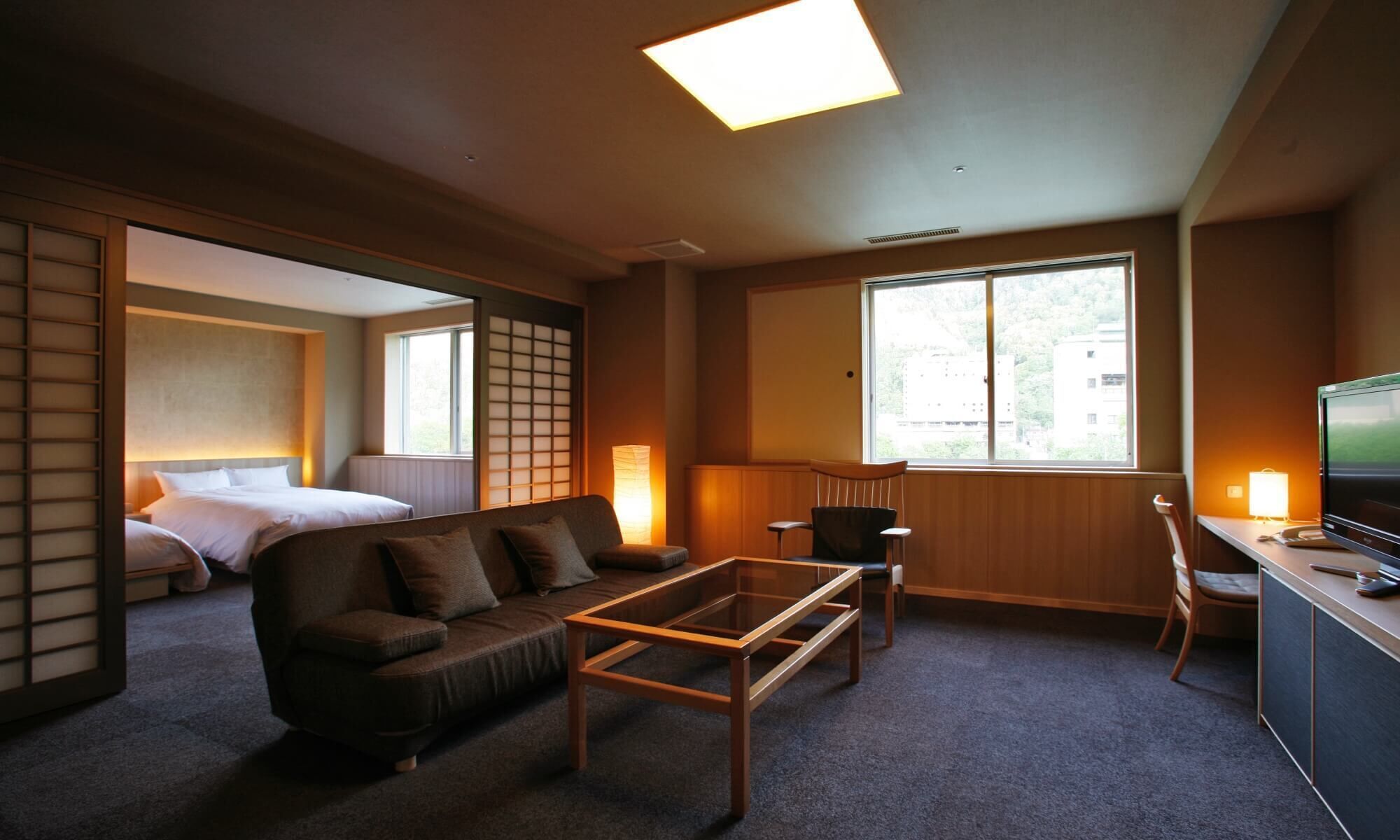 Une chambre d’hôtel avec un canapé, une petite table, un bureau avec une télévision, une chaise et un lit.