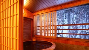 Un espace de détente en bois comprenant un bain à remous, des murs en bois et une fenêtre donnant sur la forêt.