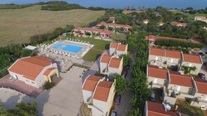 An aerial view of a resort with multiple buildings, a swimming pool, and a view of the sea. - Fournia Village (Andravida-Kyllini)