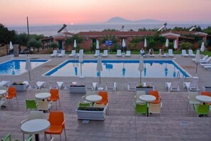 A poolside area with multiple pools, lounge chairs, and tables. - Fournia Village (Andravida-Kyllini)