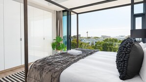A modern bedroom with a large bed, a view of the city, and a potted plant. - Warwick 504 (Cape Town)