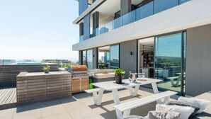 A modern outdoor patio with a barbecue, seating, and a view of the city. - Warwick 504 (Cape Town)