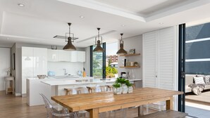 A modern kitchen with white cabinets, a wooden dining table, and pendant lighting. - Warwick 504 (Cape Town)