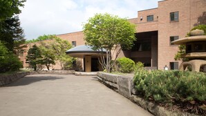 A courtyard with a brick building, a covered seating area, and a stone fountain.