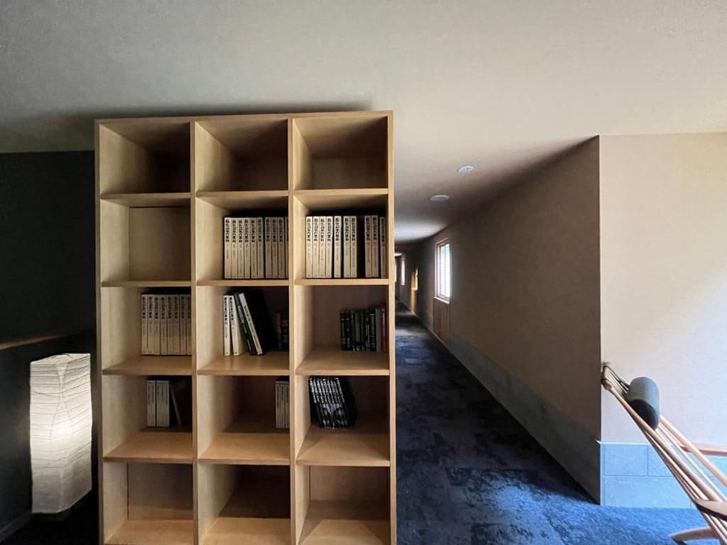 Una habitación con una gran estantería de madera llena de libros, una silla y una lámpara.