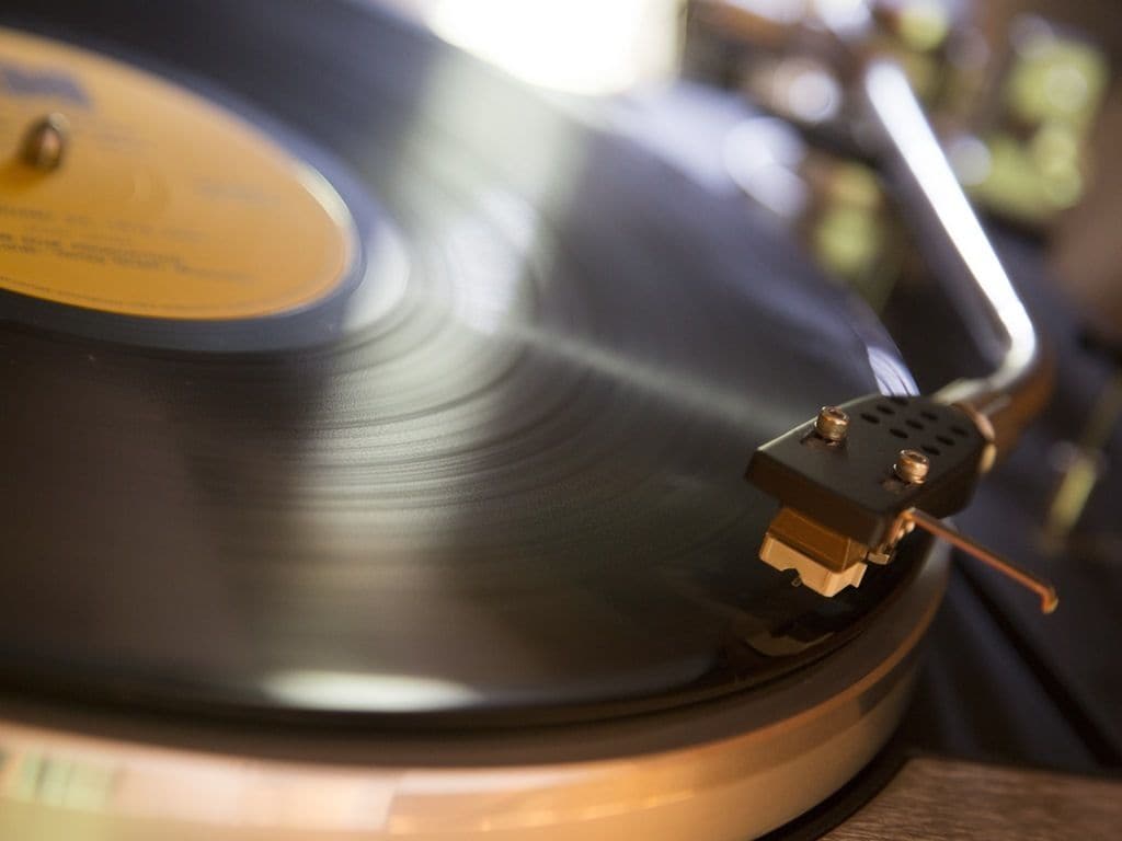 Gros plan d’un disque vinyle, avec son étiquette et son bras de lecture.