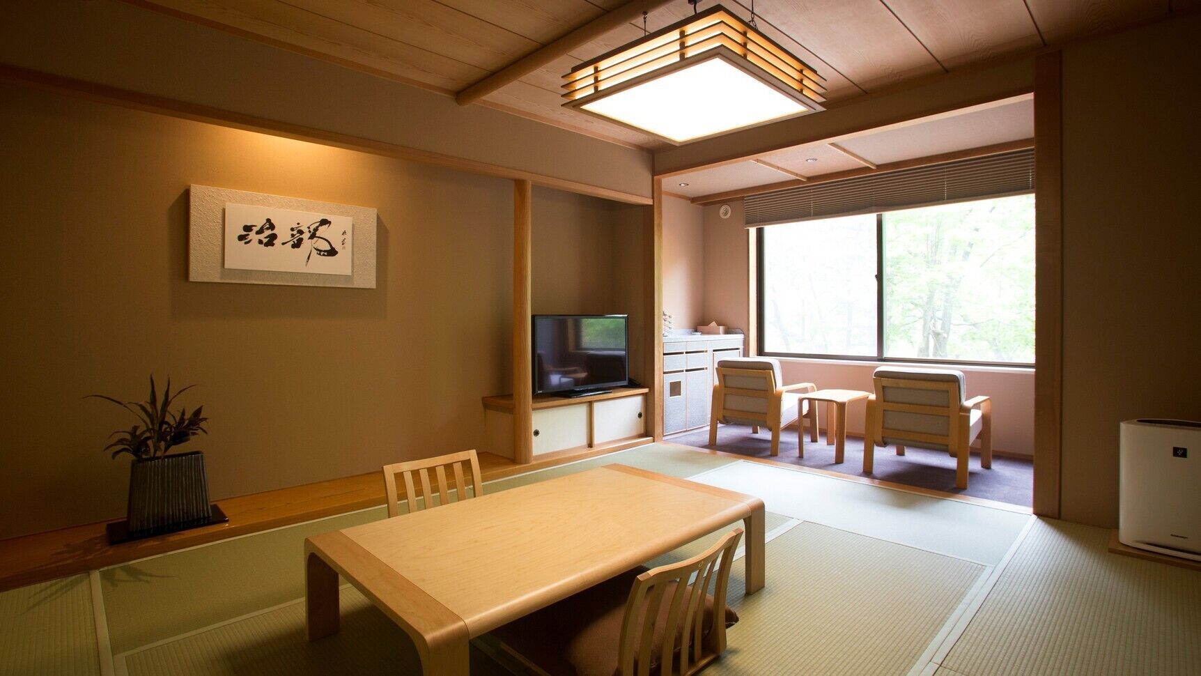 A traditional Japanese room with tatami flooring, a low table, chairs, a television, and a large window.
