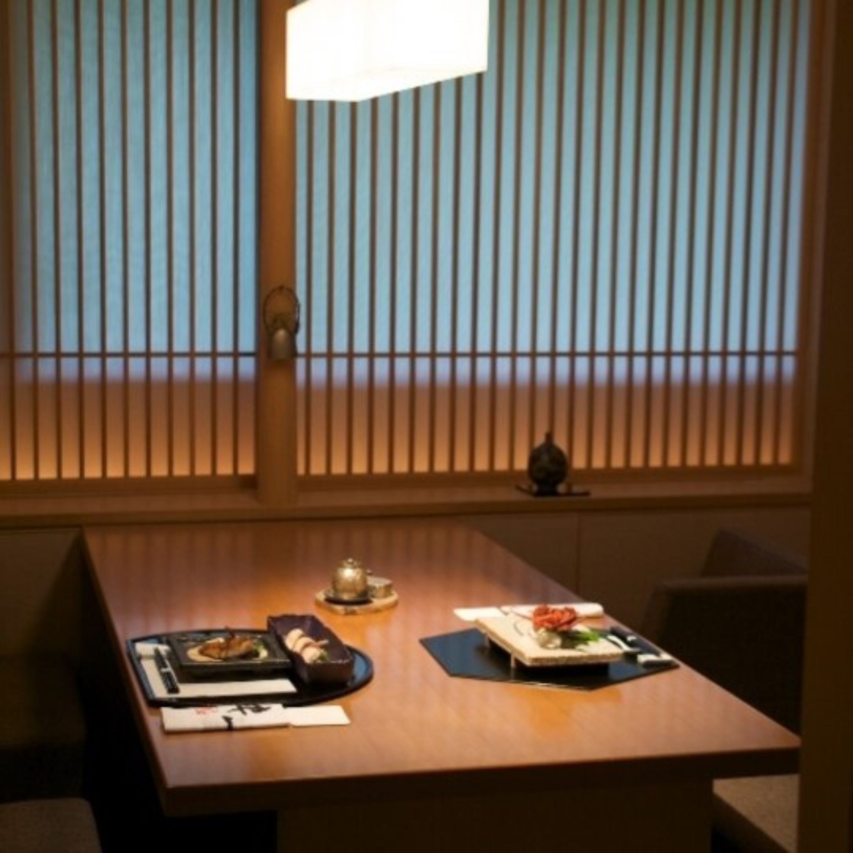 A dining table with a meal set, a decorative item, and a window with vertical blinds.