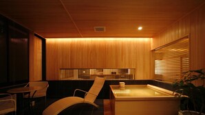 Ein moderner Spa-Bereich mit Holzboden, einer Whirlwanne, einem Liegestuhl und einem kleinen Tisch.