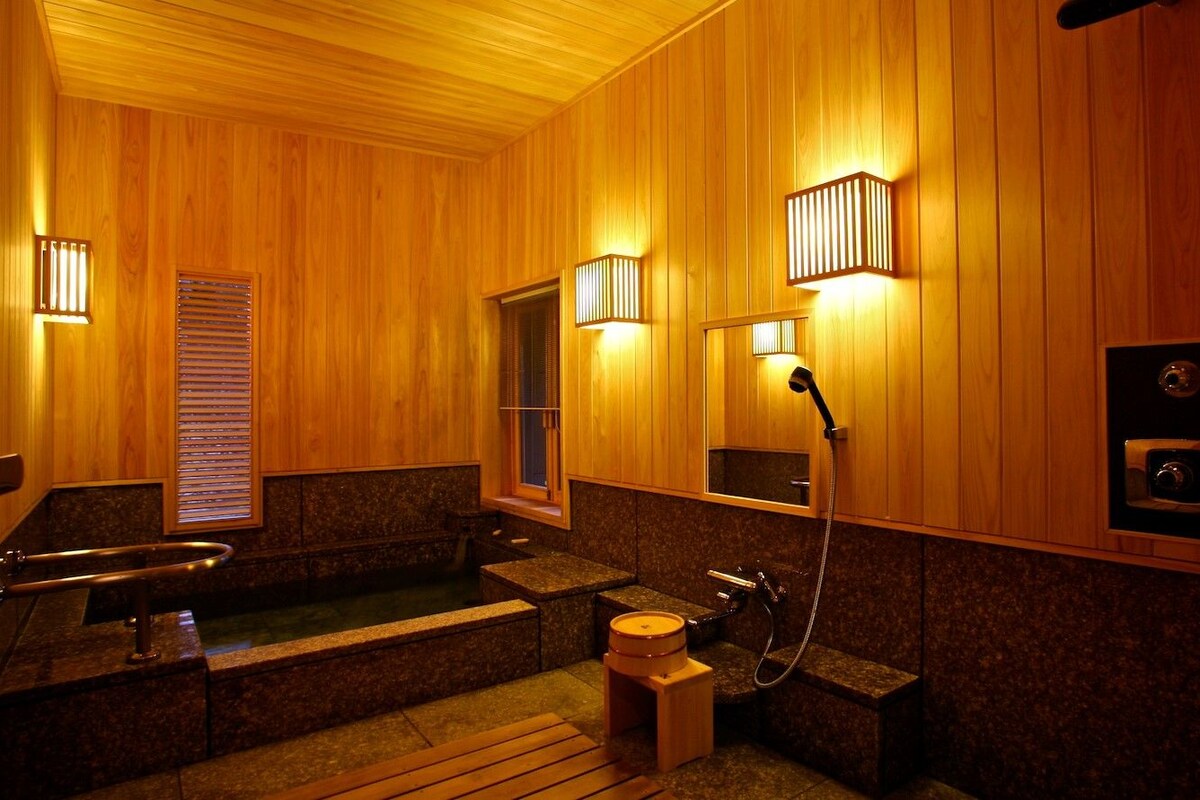 A wooden interior with a bathtub, a shower, and a toilet.