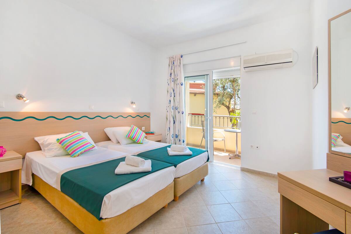 Ein Hotelzimmer mit zwei Betten, einem Balkon und einer Klimaanlage.
