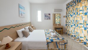 A hotel room with a bed, a desk, a chair, a lamp, a window, and a curtain. - Hidden garden Rhodes Apartments (Rhodes)