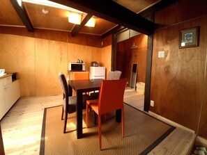 A compact dining area with a wooden table and chairs, a microwave, and a refrigerator. - Yanaka No Taisuke (Gujo)