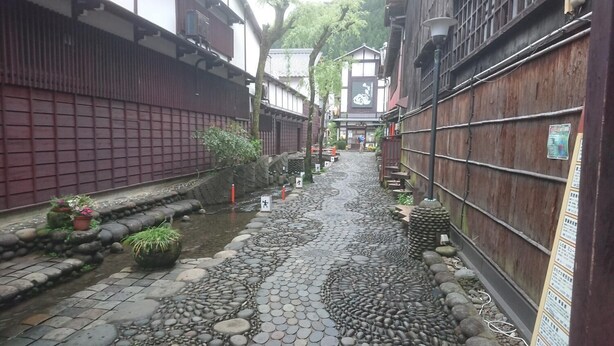 A narrow alley with stone paving, wooden fences, and traditional buildings. - Yanaka No Taisuke (Gujo)