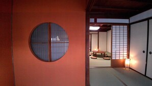 A traditional Japanese room with tatami flooring, a shoji screen door, and a round window with a grid pattern. - Yanaka No Taisuke (Gujo)