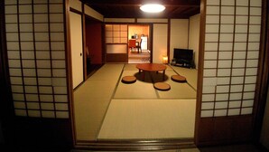 A traditional Japanese room with tatami flooring, a low table, cushions, and a television. - Yanaka No Taisuke (Gujo)