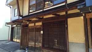 A traditional Japanese building with a wooden structure, large sliding doors, and a small garden area with a potted plant. - Yanaka No Taisuke (Gujo)