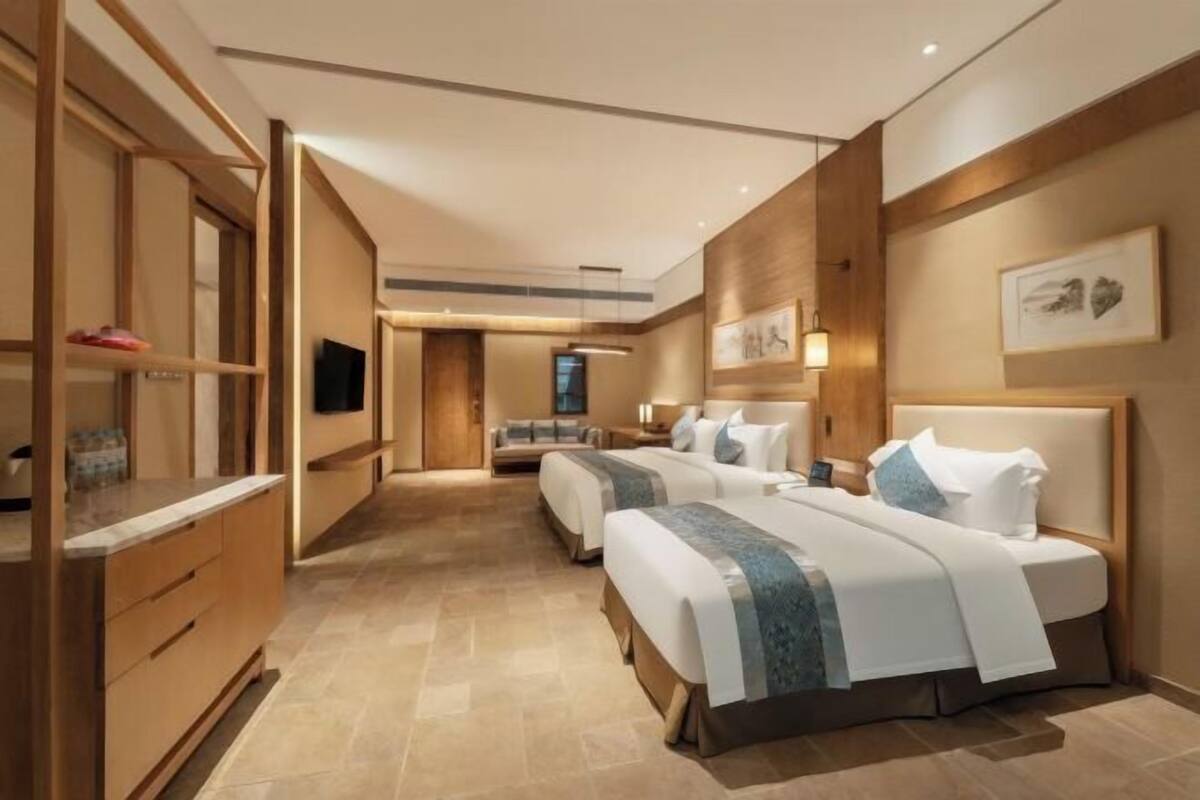 A hotel room with a large bed, a desk, and a wardrobe.
