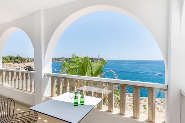 A balcony with a table and chairs overlooking a coastal view.