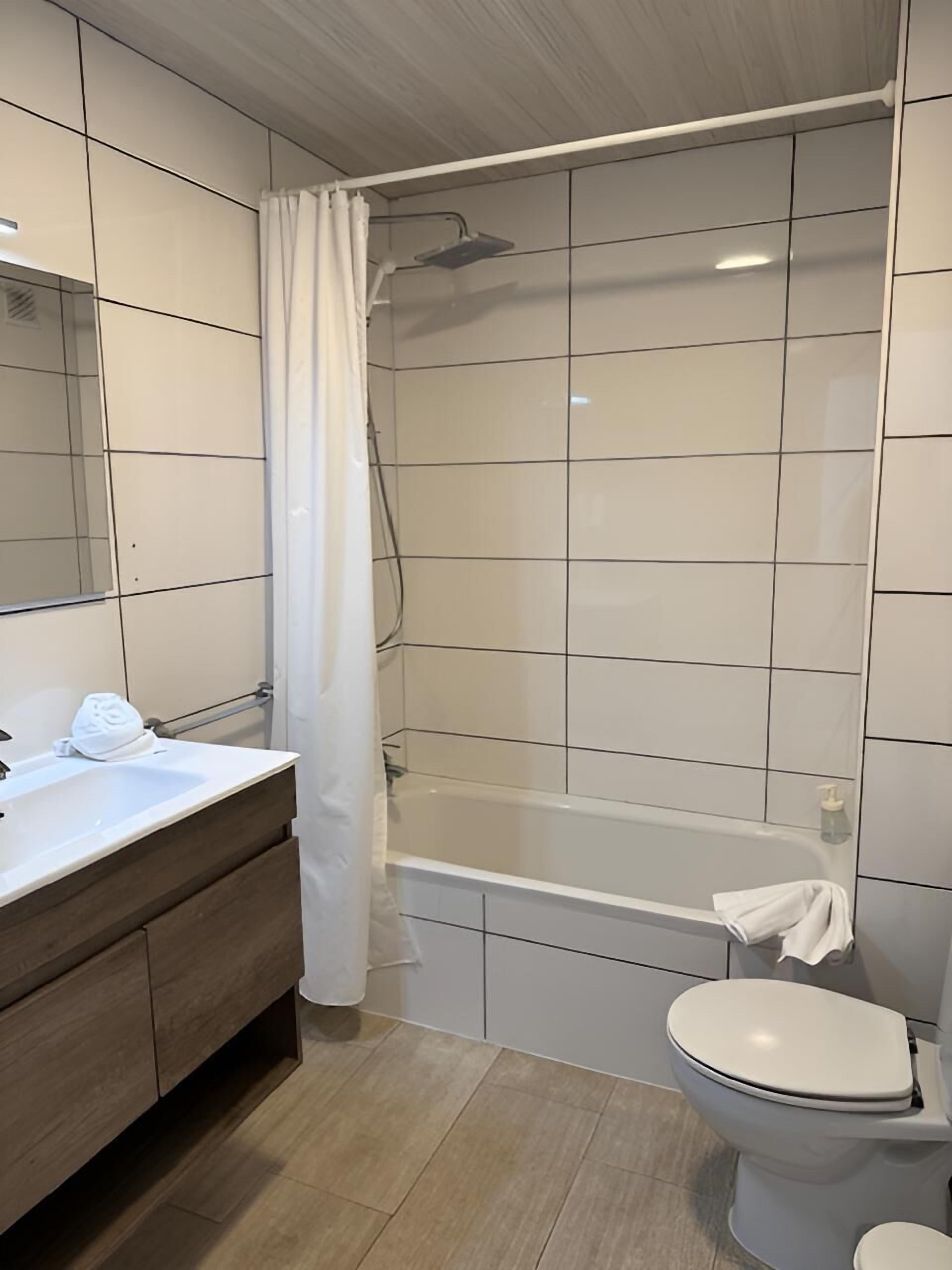 A modern bathroom with a bathtub, toilet, and vanity.