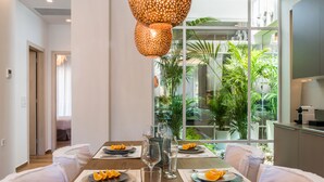 A dining table set with plates, cutlery, and glasses, with a view of indoor plants through a window. - No17 Pireos Street (Chania)
