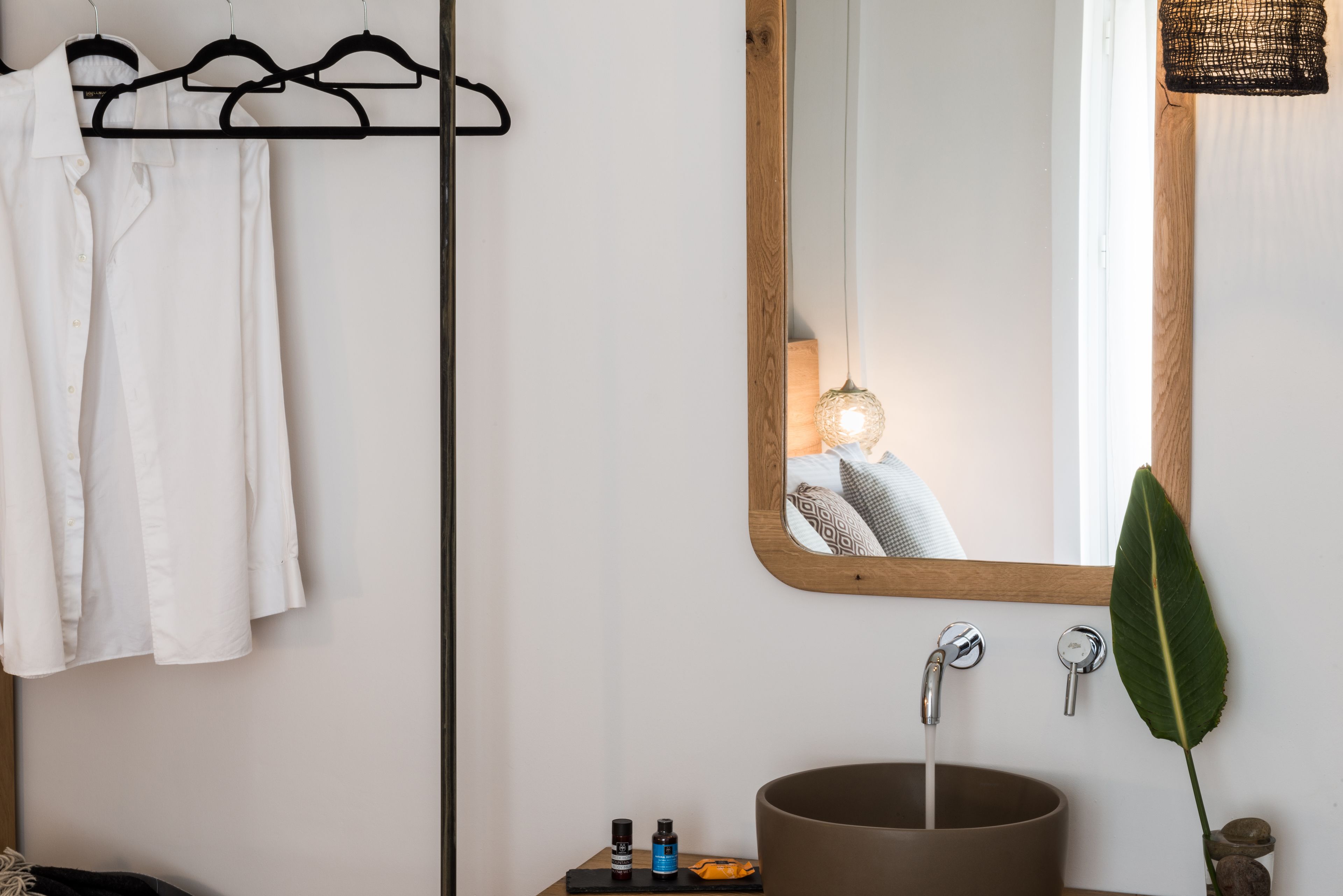 A bathroom with a wooden-framed mirror, a round sink, and a towel rack with white towels.