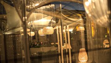 Un espacio al aire libre con mesas y sillas, un gran accesorio de iluminación decorativo y un paseo techado.