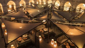 Une terrasse sur le toit dotée de plusieurs espaces de détente, comprenant des canapés et des tables rondes, le tout abrité par de grands auvents.